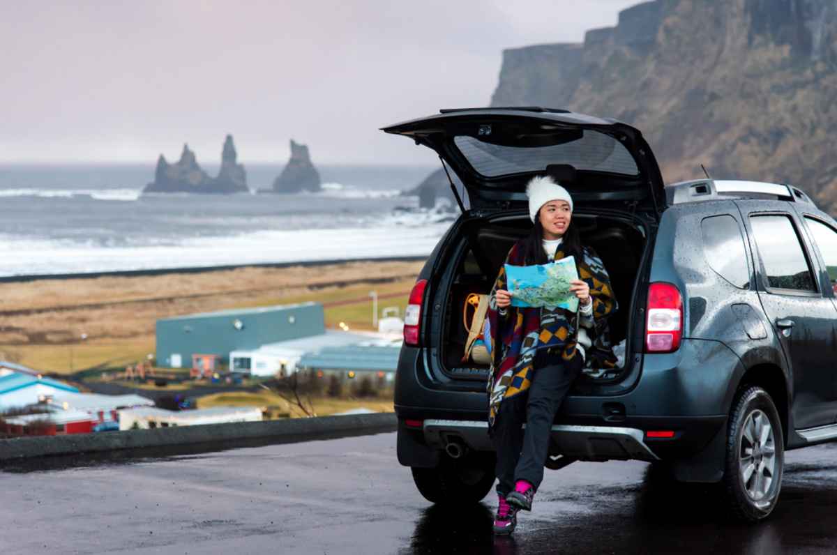 Best 4x4 cars to rent in Iceland Tourist sitting in the trunk of her 4x4 rental in Iceland
