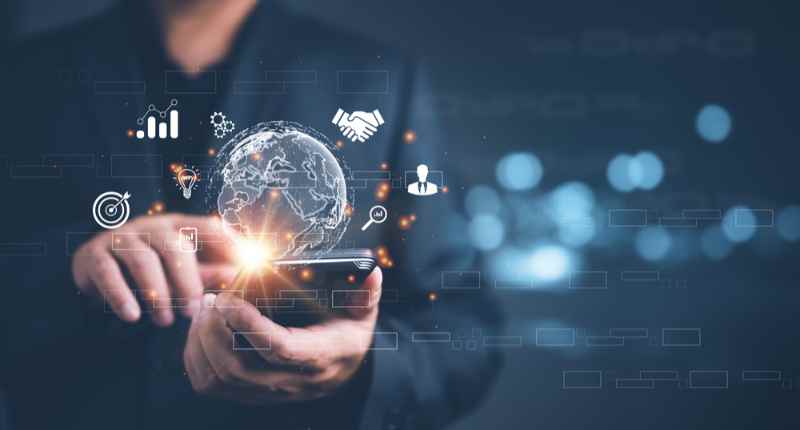 Technology and global business: smartphone usage with digital symbols Businessman uses smartphone while digital icons like a globe and business graphics float in the air.